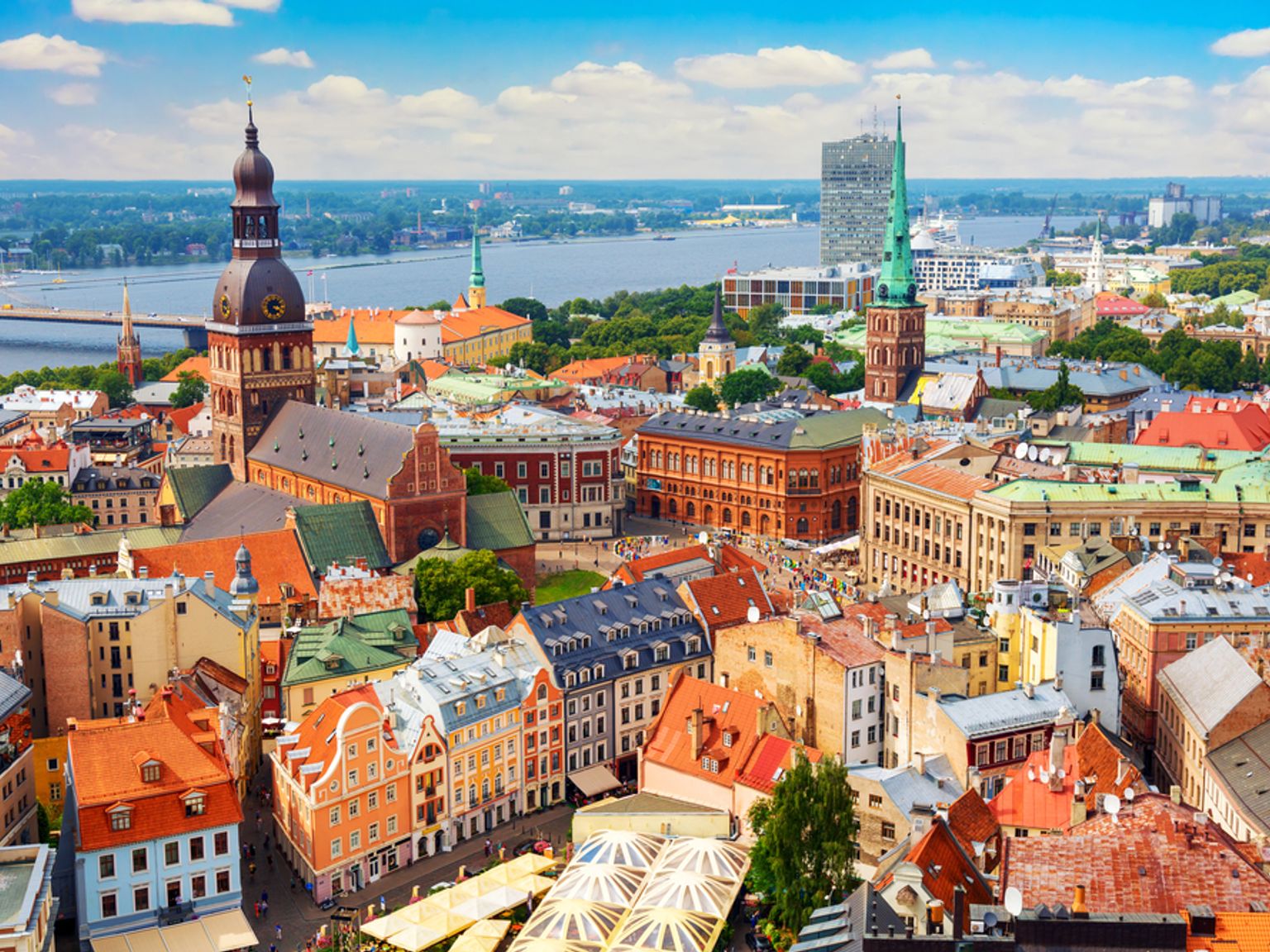 Luftfoto af en historisk europæisk by med farverige bygninger, en flod og markante kirkespir.