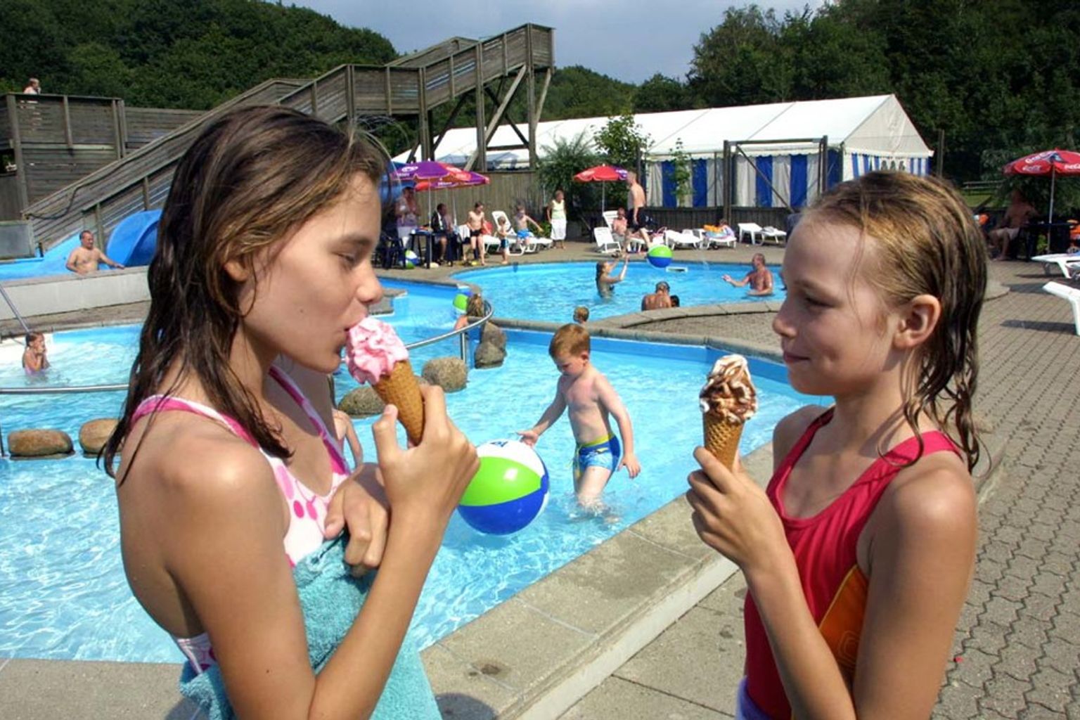 dwie dziewczynki jedzą lody przed basenem