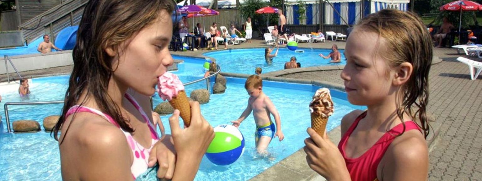 dwie dziewczynki jedzą lody przed basenem