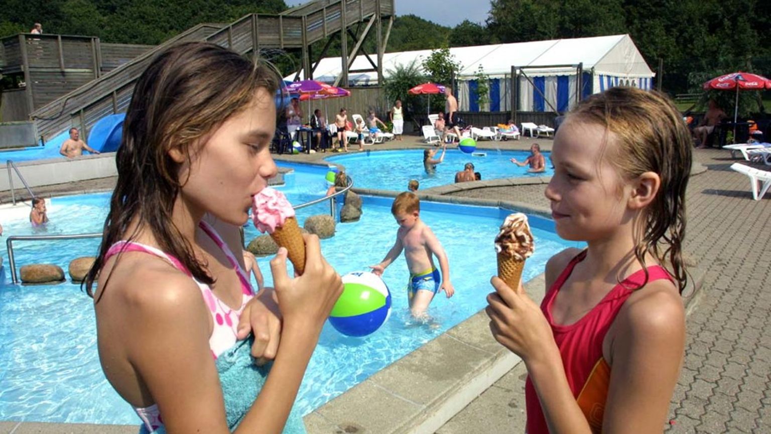 dwie dziewczynki jedzą lody przed basenem