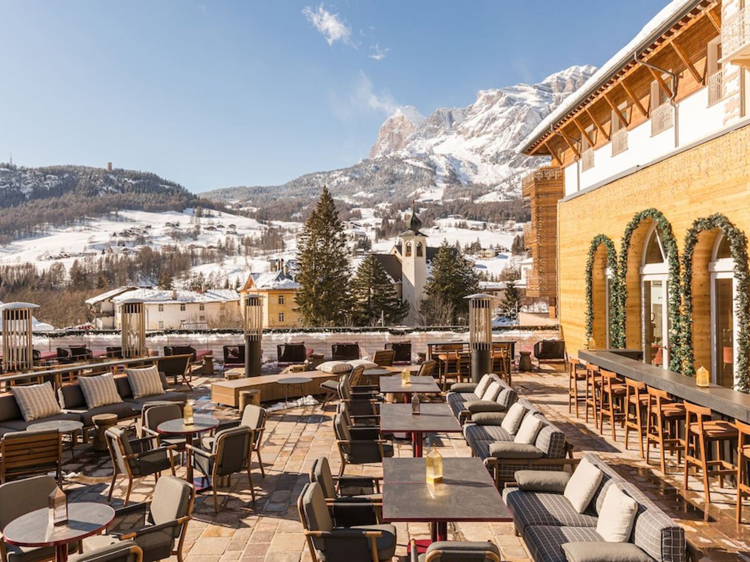 en uteplats med bord och stolar framför en byggnad med ett berg i bakgrunden, Grand Hotel Savoia Cortina d'Ampezzo, A Radisson Collection Hotel