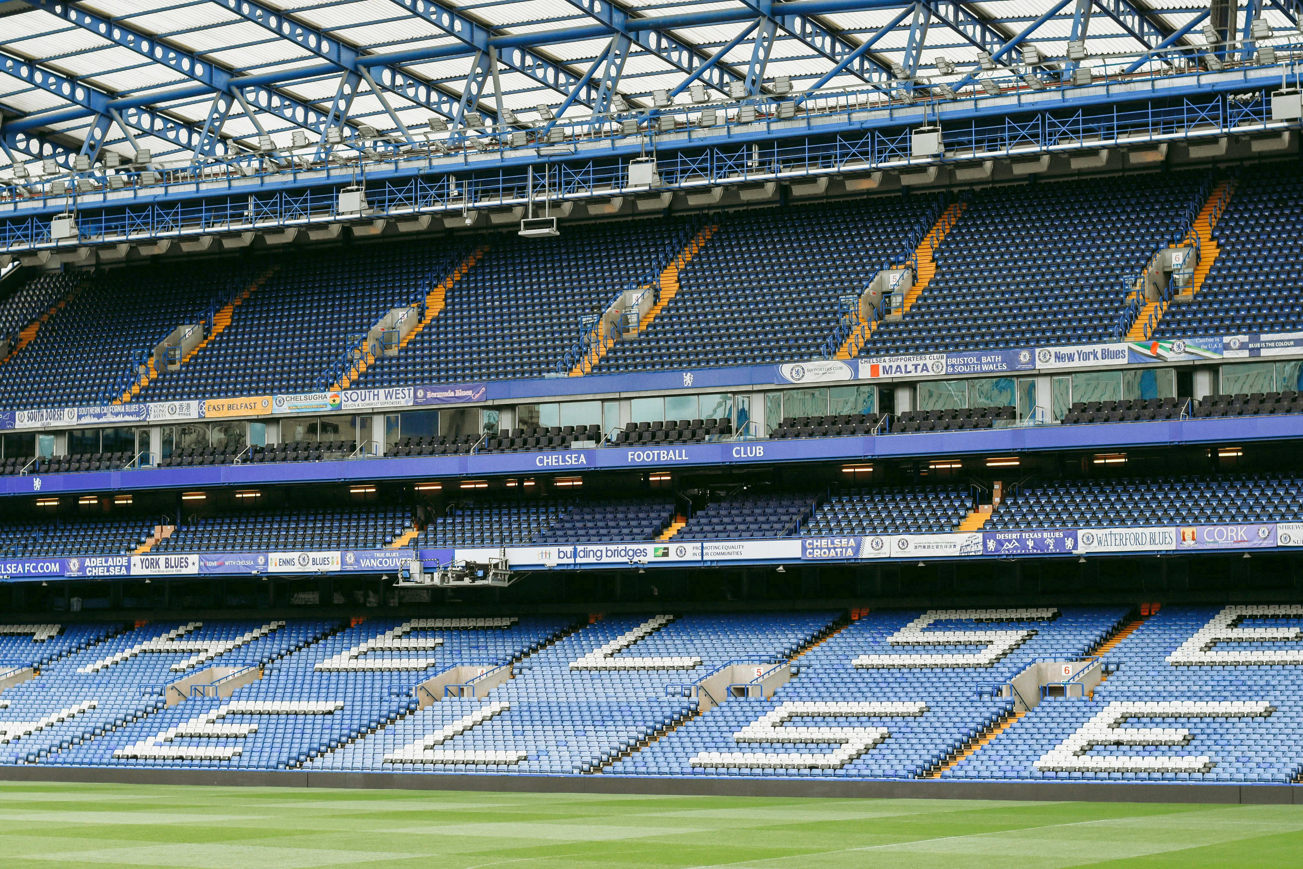 Tomt Chelsea Football Club stadion med blå og hvite seter, som staver "CHELSEA" på den nedre tier.
