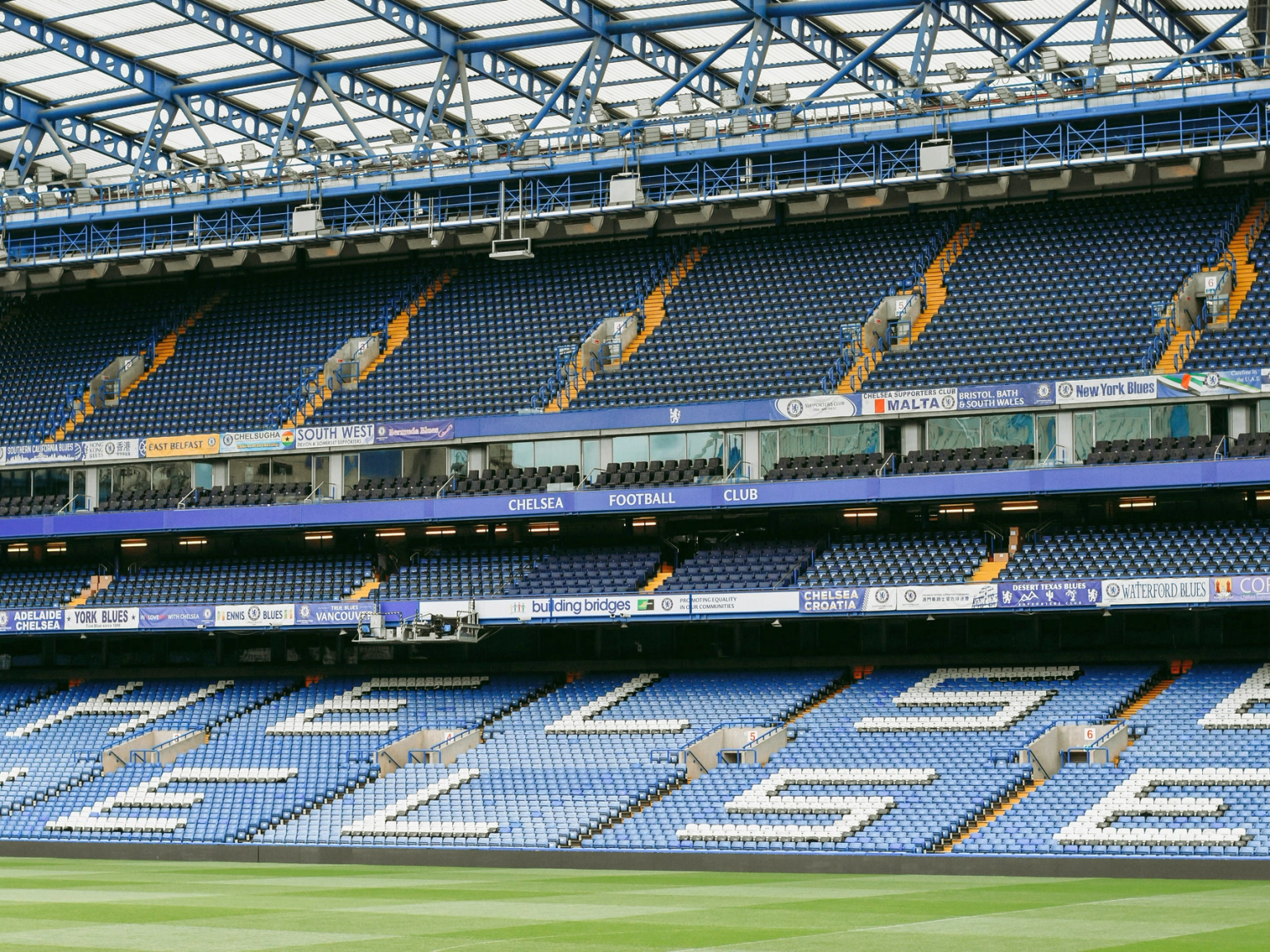 Tomt Chelsea Football Club stadion med blå og hvite seter, som staver "CHELSEA" på den nedre tier.