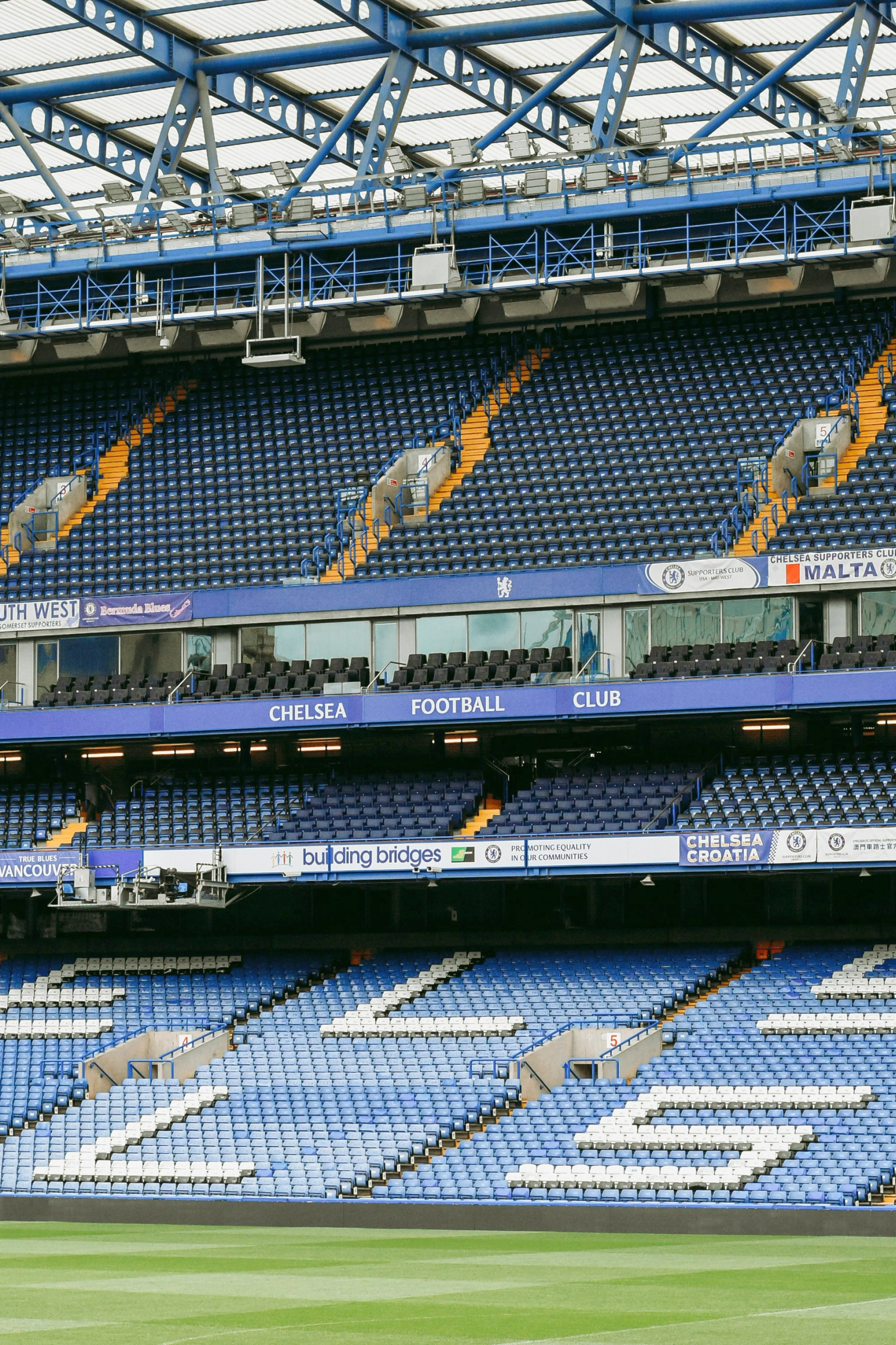 Tomt Chelsea Football Club stadion med blå og hvite seter, som staver "CHELSEA" på den nedre tier.