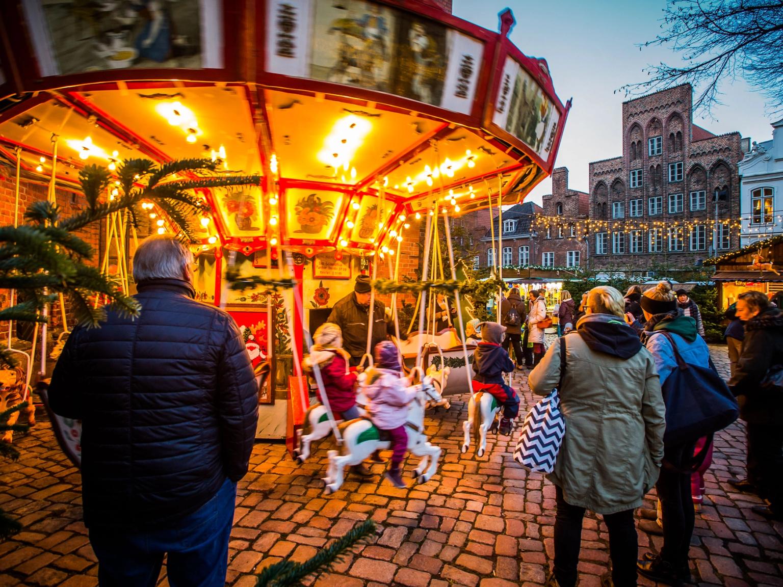 en grupp människor står runt en karusell på en julmarknad i Tyskland