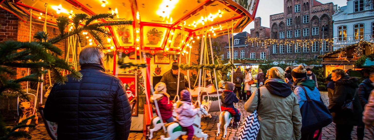 en grupp människor står runt en karusell på en julmarknad i Tyskland