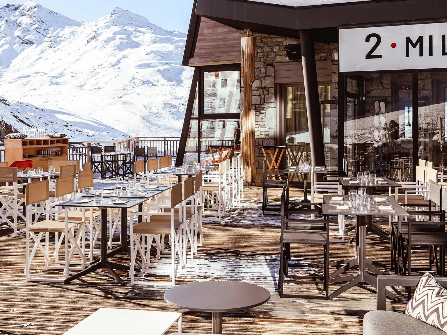 er zijn veel tafels en stoelen buiten een restaurant met bergen op de achtergrond, Altapura Hôtel & Spa Val Thorens.