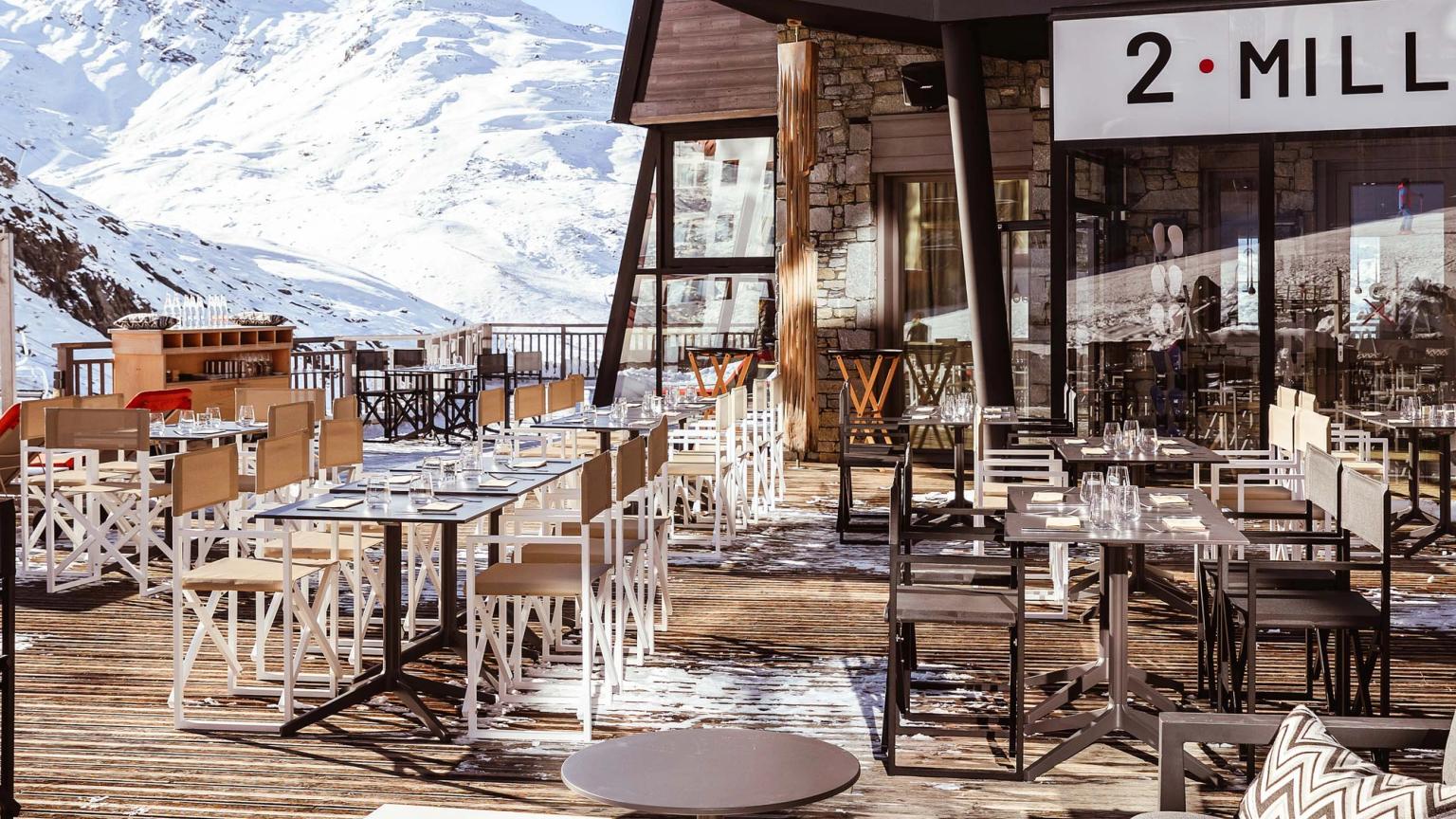 er zijn veel tafels en stoelen buiten een restaurant met bergen op de achtergrond, Altapura Hôtel & Spa Val Thorens.
