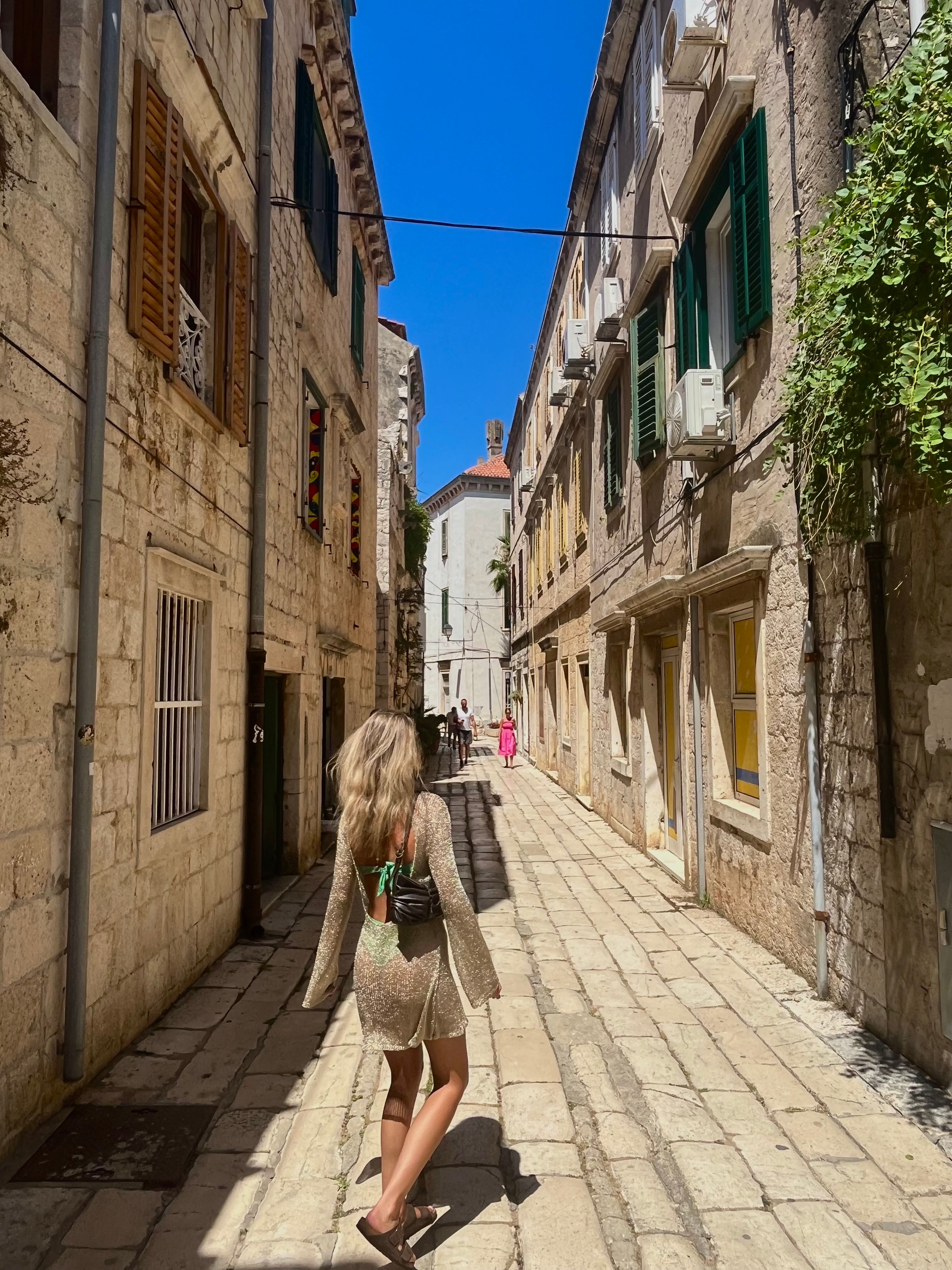 Une femme en robe scintillante marchant dans les rues de Vis, en Croatie