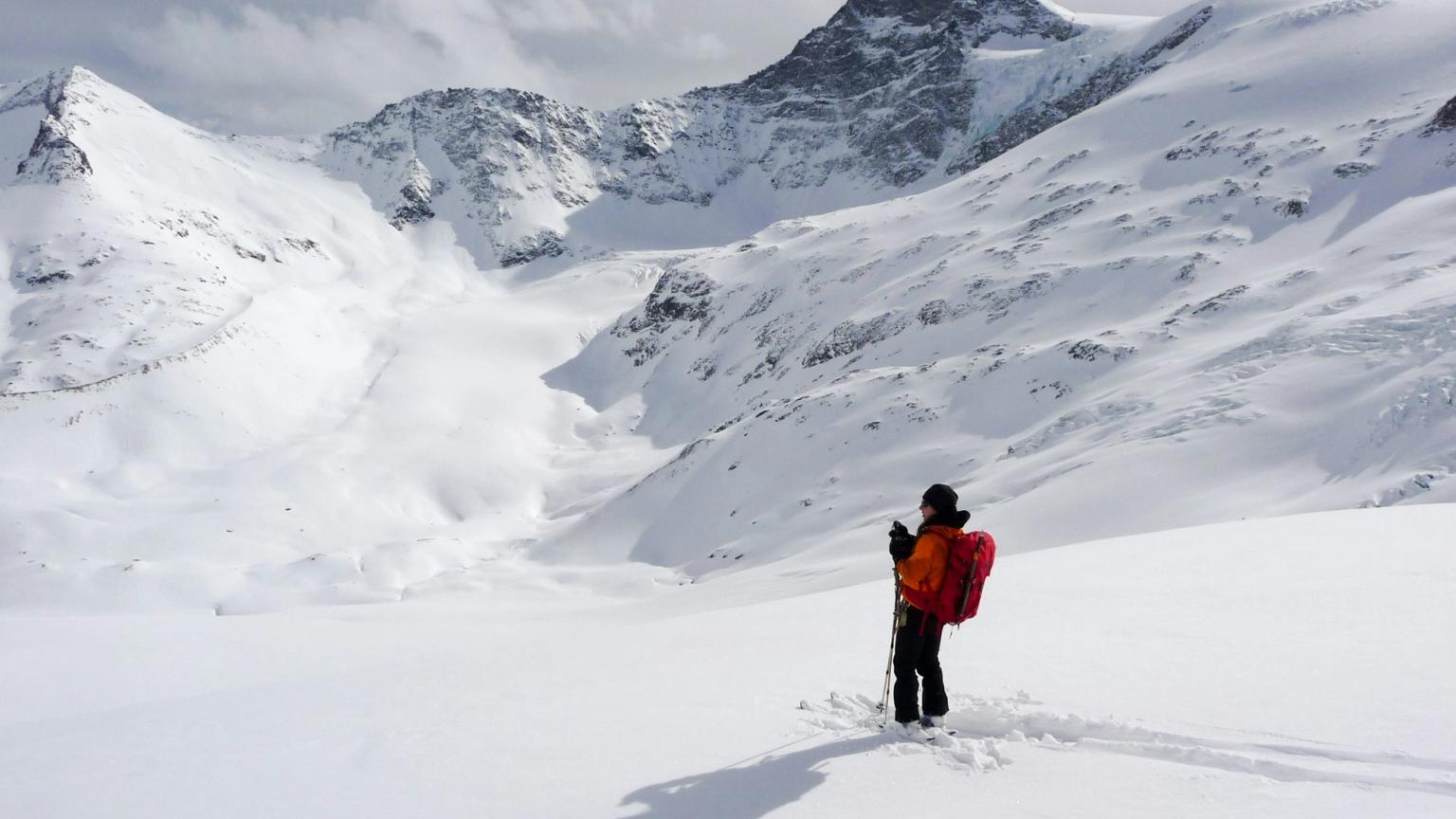 en person står i snøen på toppen av et snødekt fjell