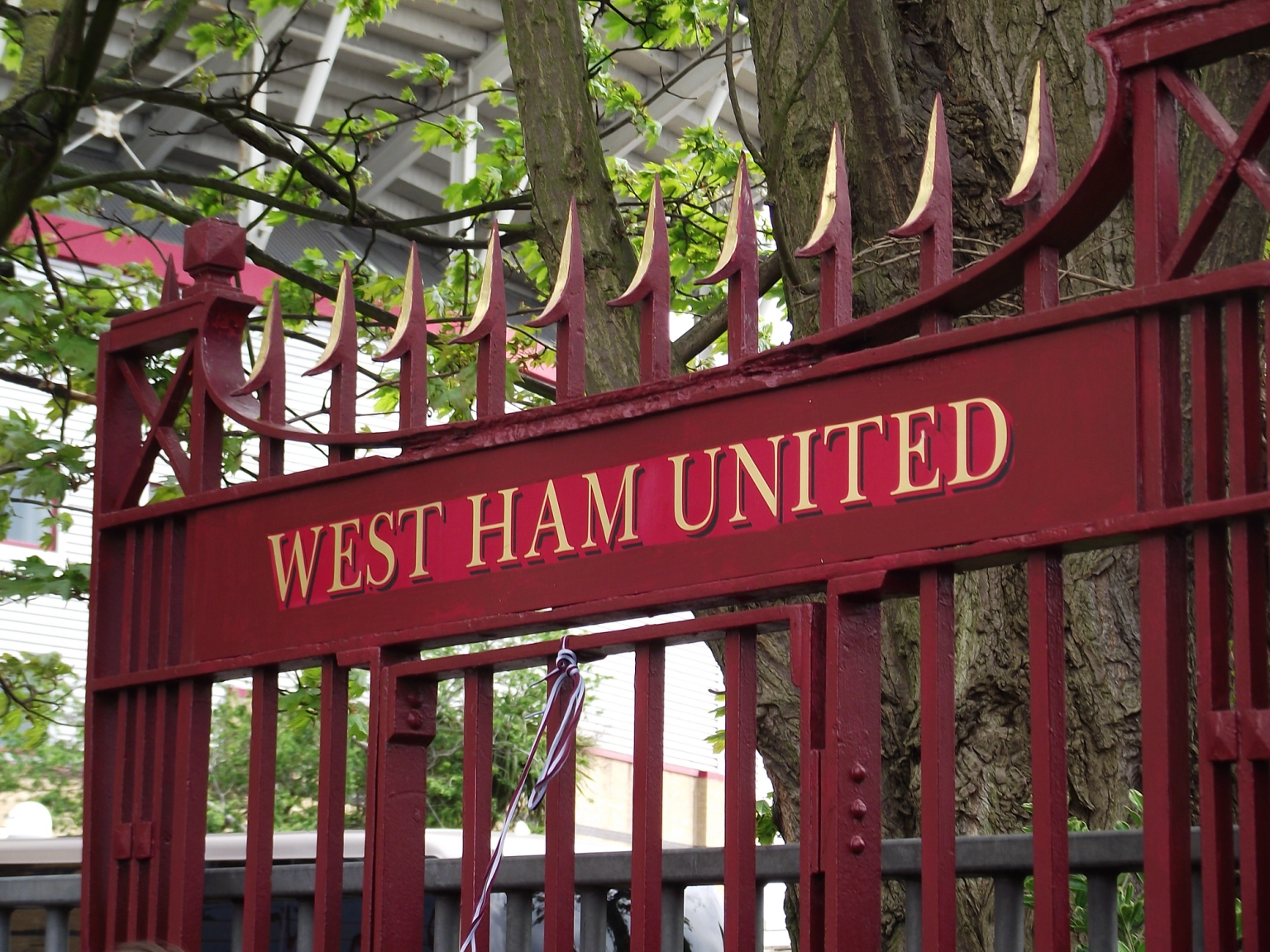 Rød port med "WEST HAM UNITED" i guldbogstaver og guldtippede pigge på toppen.