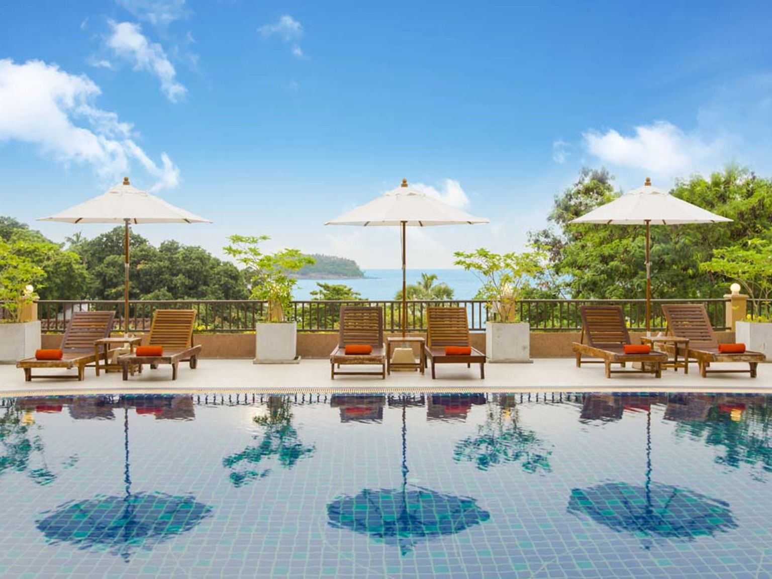 en simbassäng med stolar och paraplyer och utsikt över havet