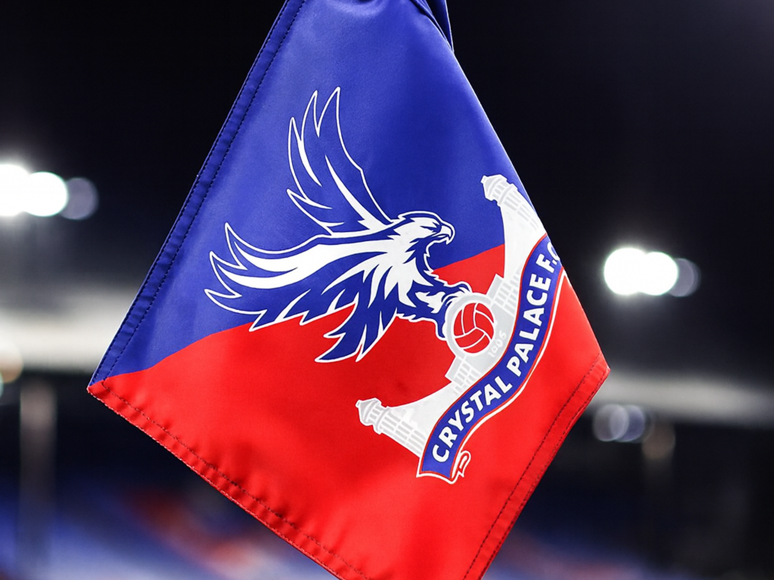A Crystal Palace F.C. corner flag on a football pitch at night.