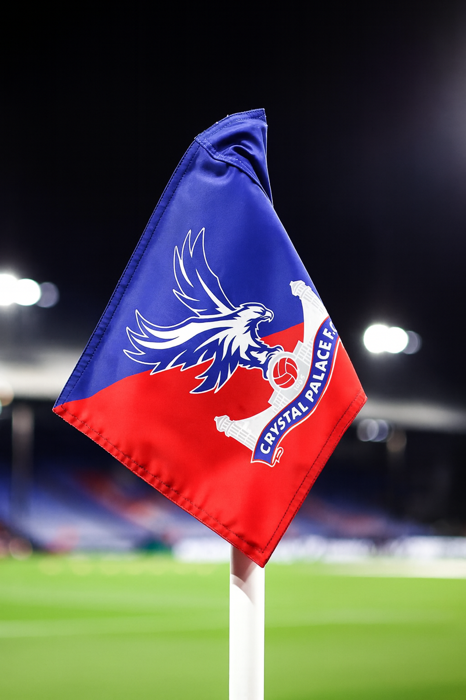 A Crystal Palace F.C. corner flag on a football pitch at night.