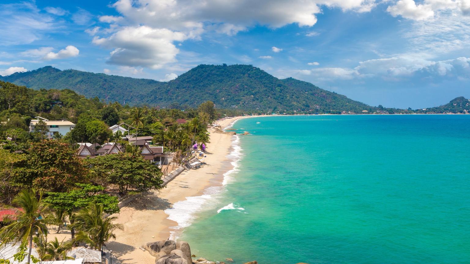 en luftig utsikt over en tropisk strand med fjell i bakgrunnen