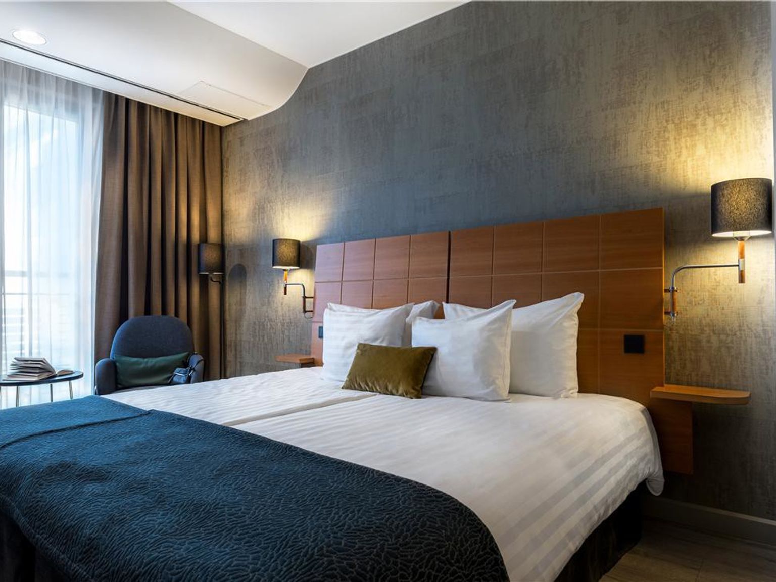 a hotel room with a large bed and a chair