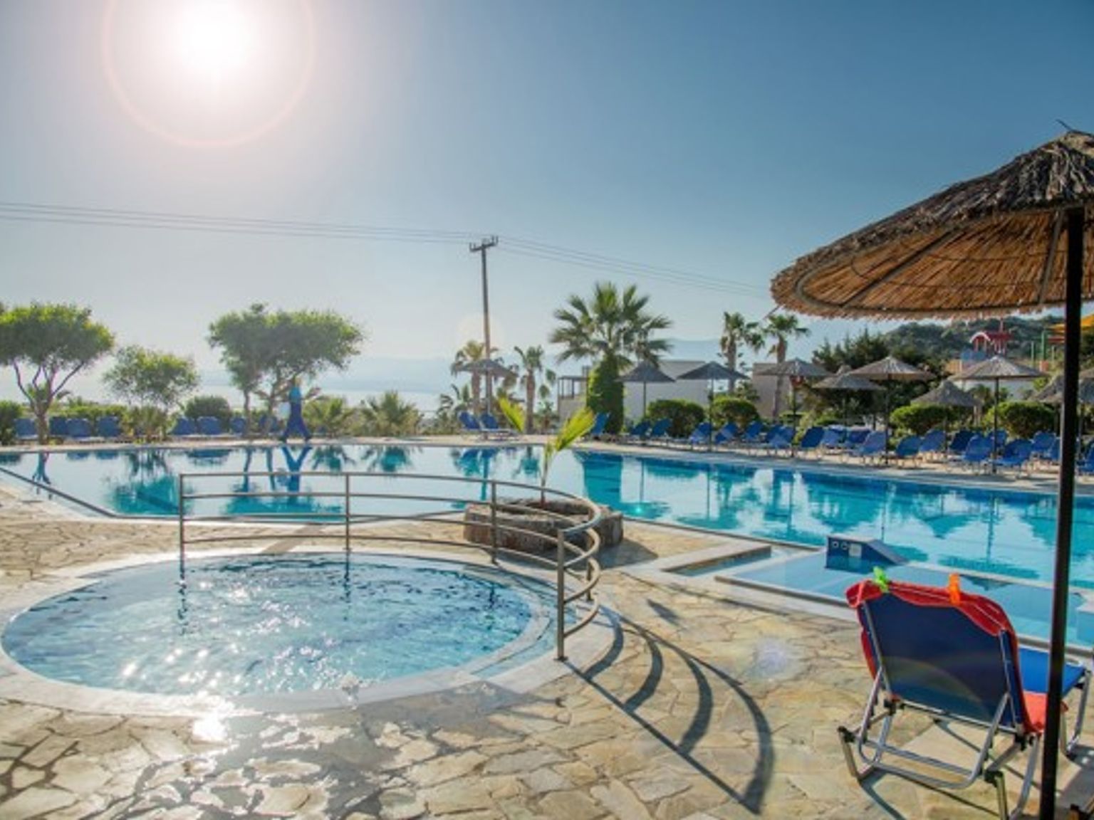 en stor swimmingpool omgivet af stole og paraplyer på en feriested