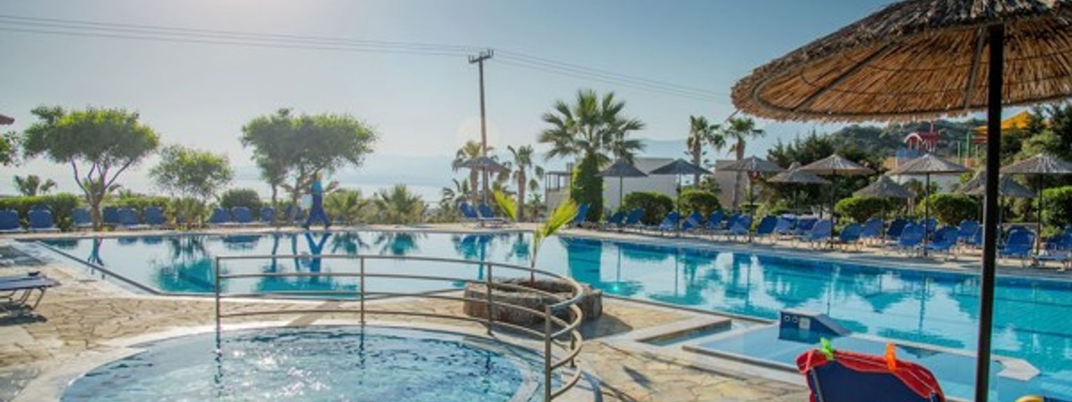 en stor simbassäng omgiven av stolar och paraplyer på en resort