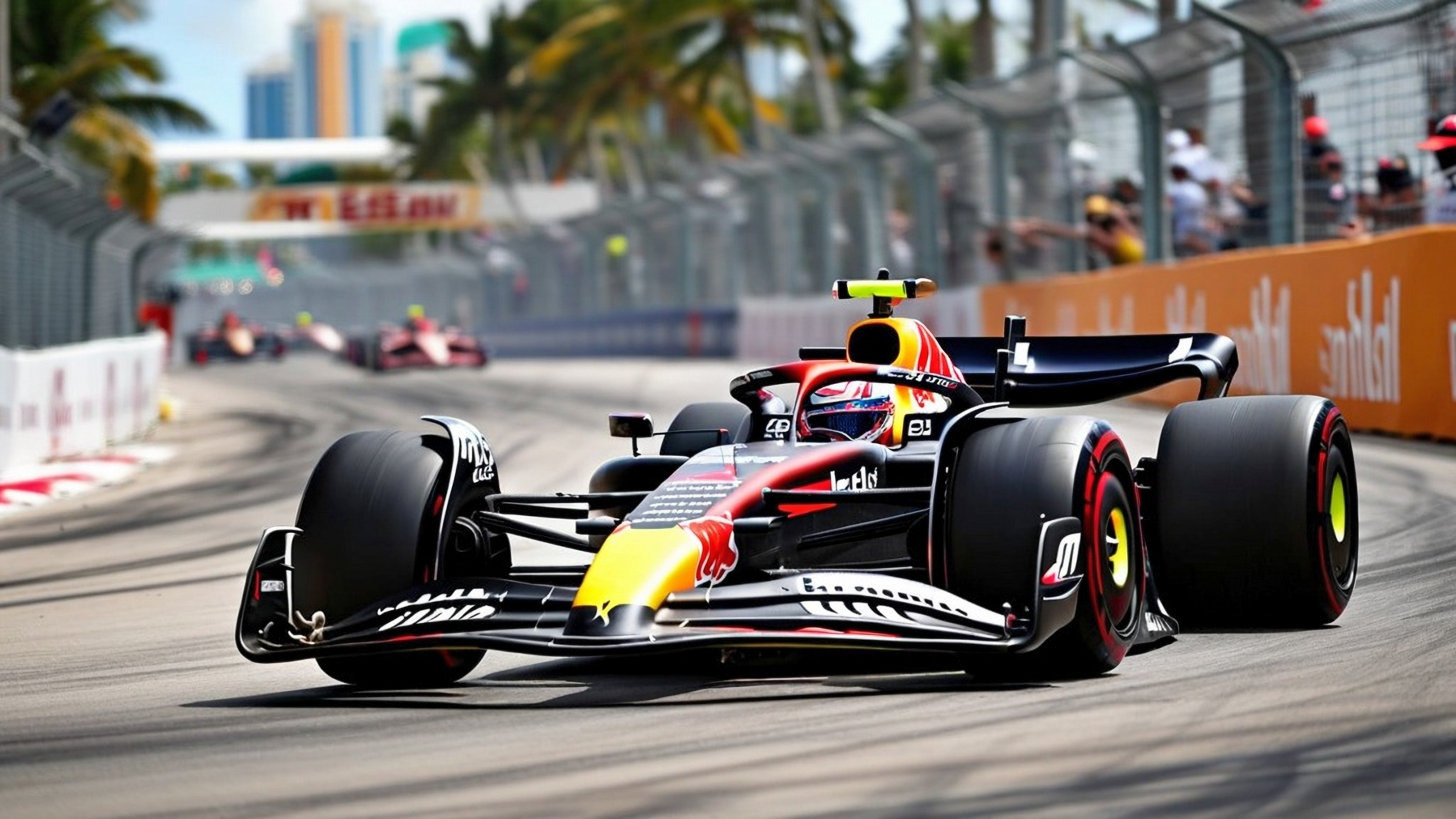 Red Bull Formula 1 car racing on a street circuit with city buildings in the background.