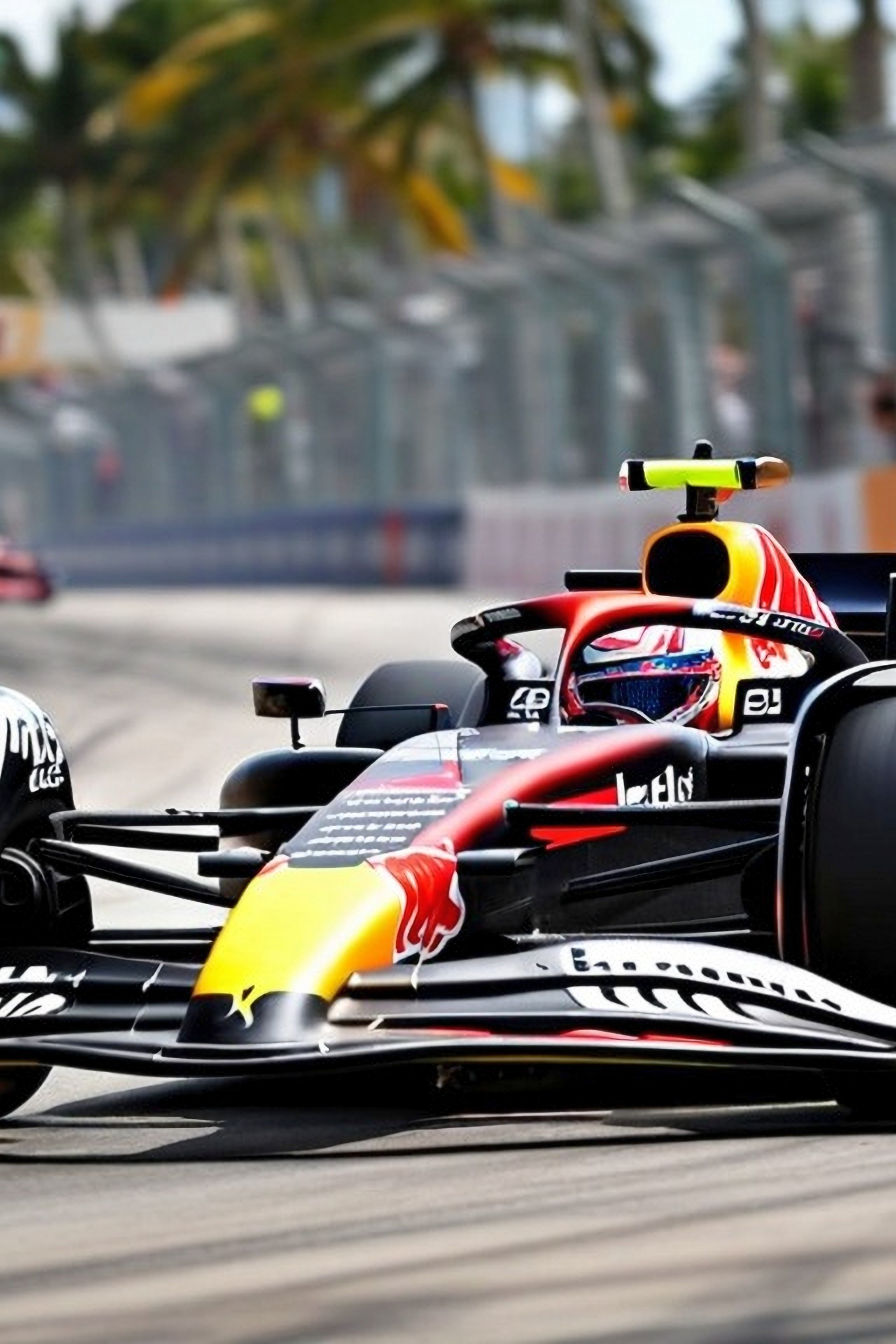 Red Bull Formula 1 car racing on a street circuit with city buildings in the background.