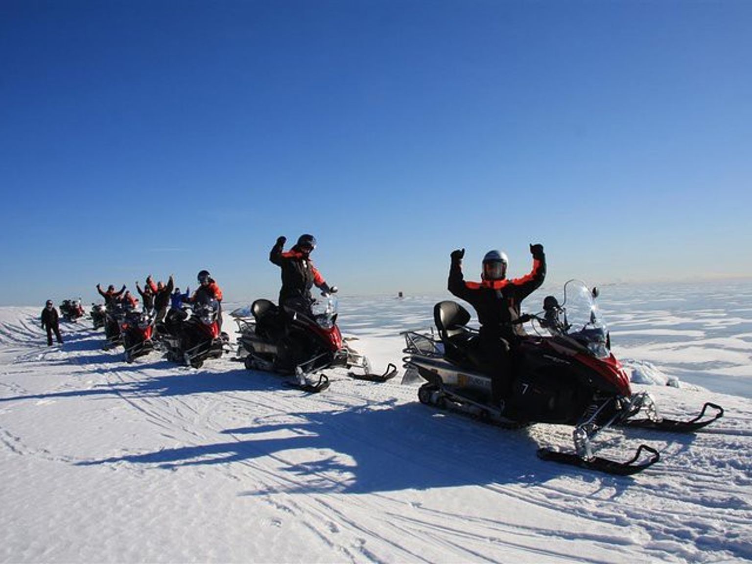 a group of people are riding snowmobiles in the snow