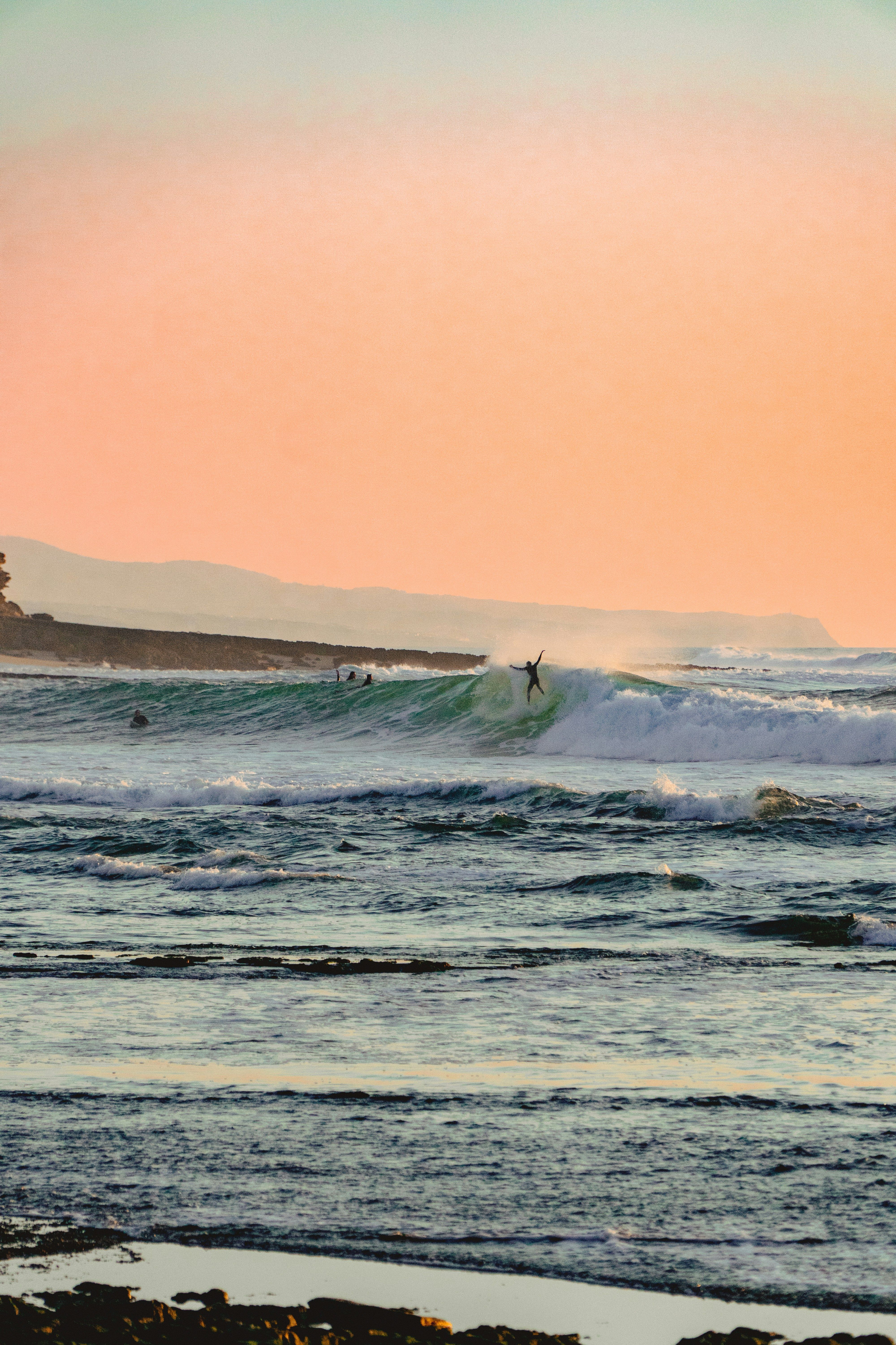 a surfer rides a wave in the ocean at sunset