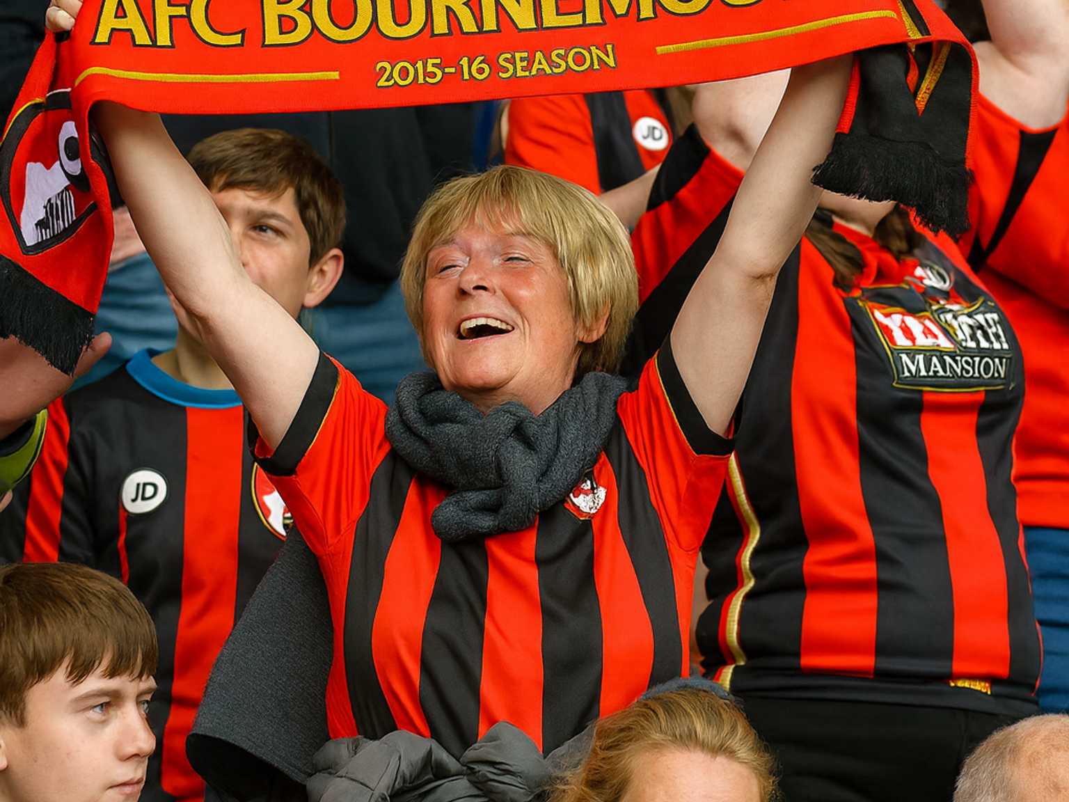 Fröhliche Frau im Stadion hält einen AFC Bournemouth 2015-16 Premier League-Schal hoch.