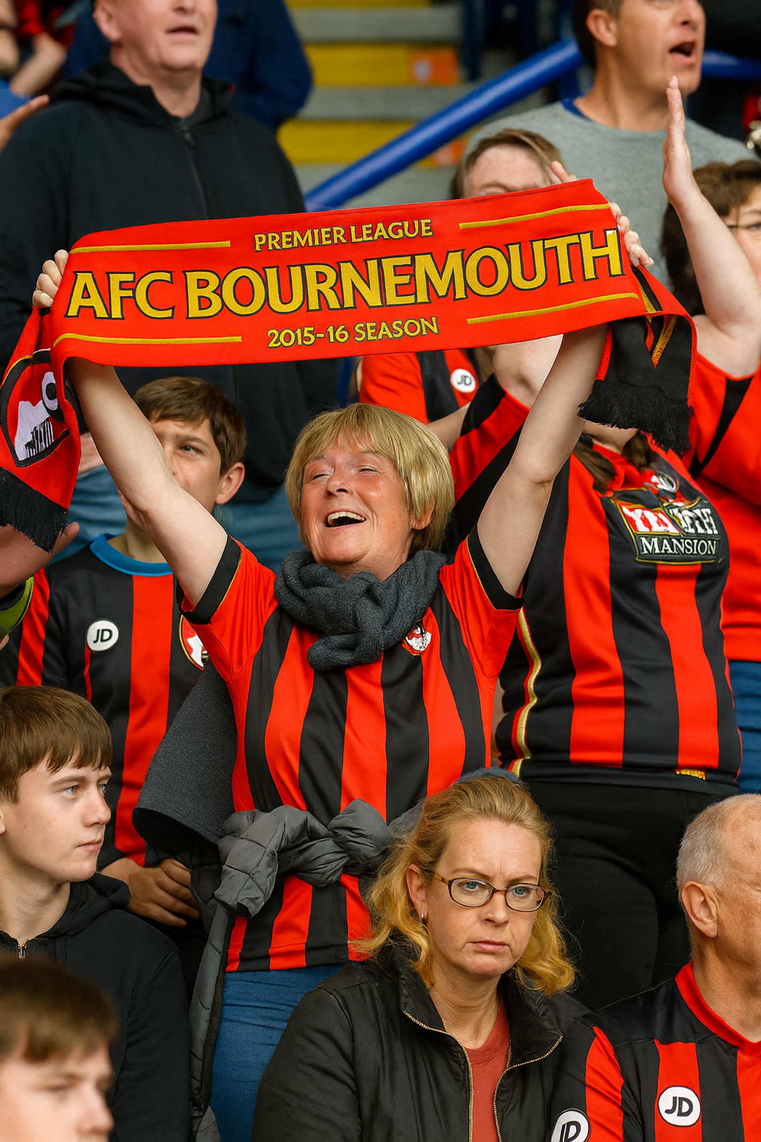 Fröhliche Frau im Stadion hält einen AFC Bournemouth 2015-16 Premier League-Schal hoch.