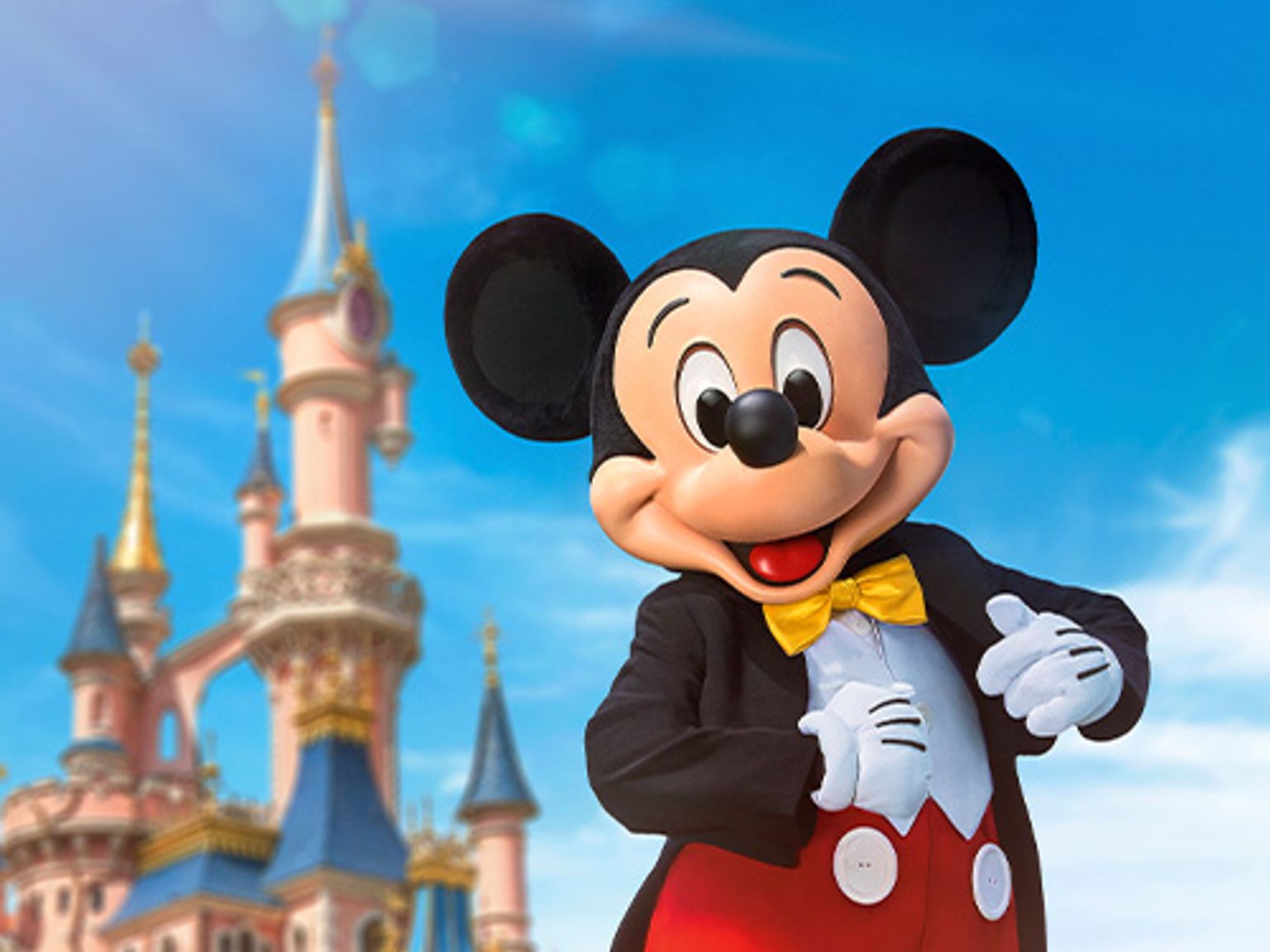 mickey mouse is standing in front of a castle.