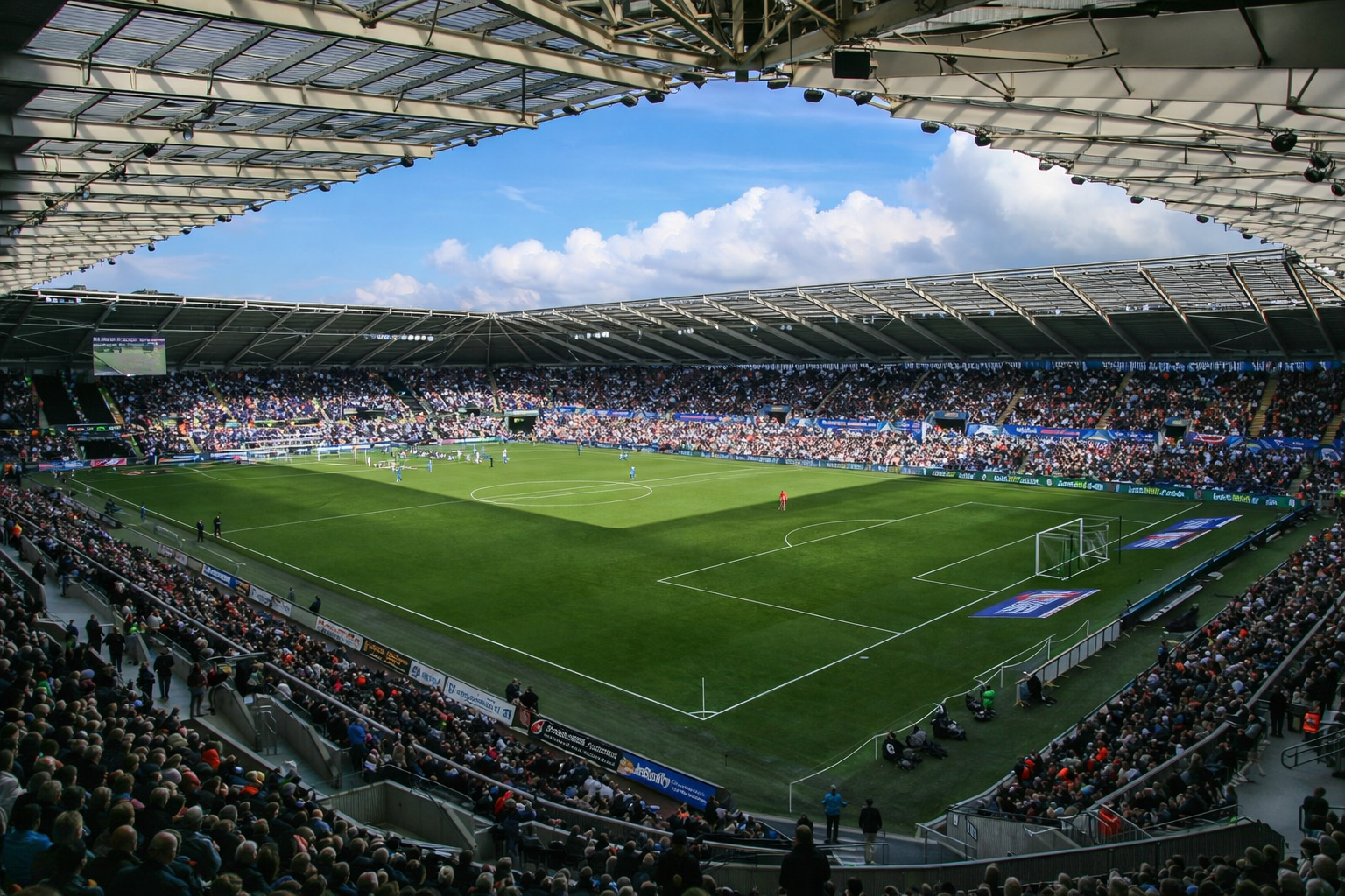 A large, packed football stadium during a match, with a clear blue sky overhead.