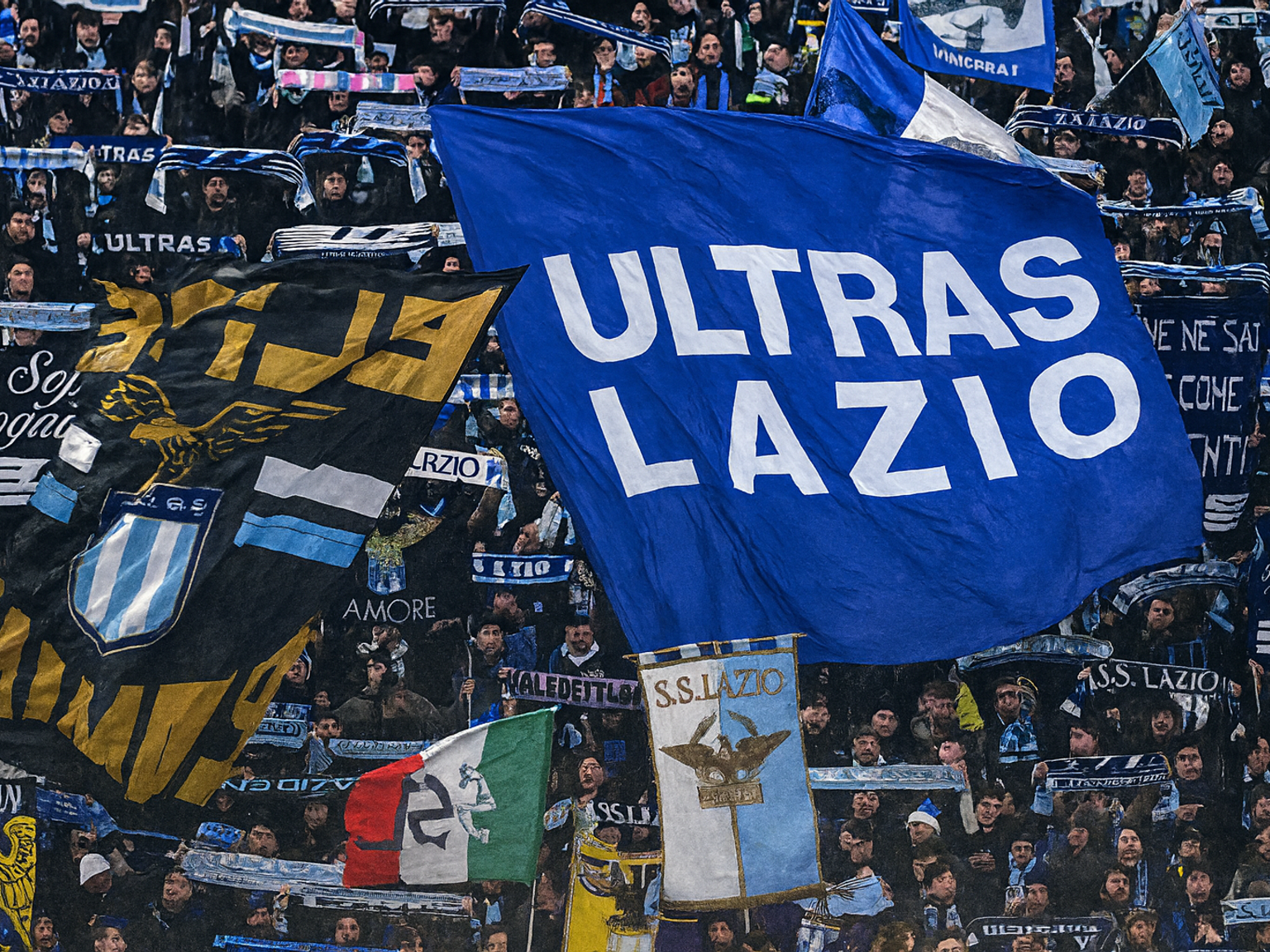 Lazio fotbollsfans håller stora flaggor, inklusive en blå med "ULTRAS LAZIO" skrivet i vitt.