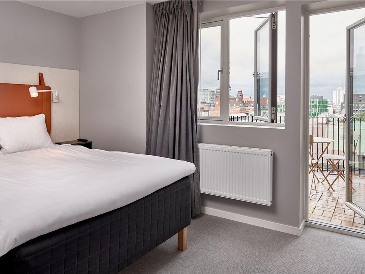 ett hotellrum med en säng, fönster och balkong