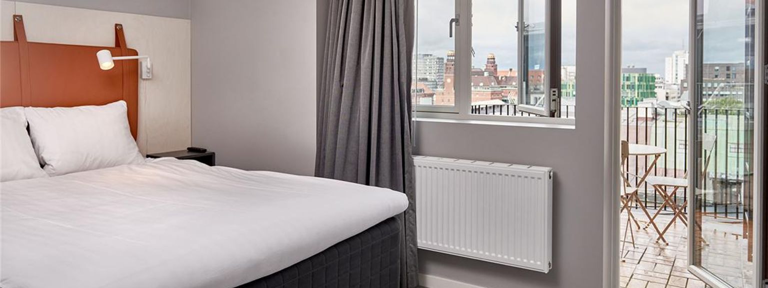 ett hotellrum med en säng, fönster och balkong