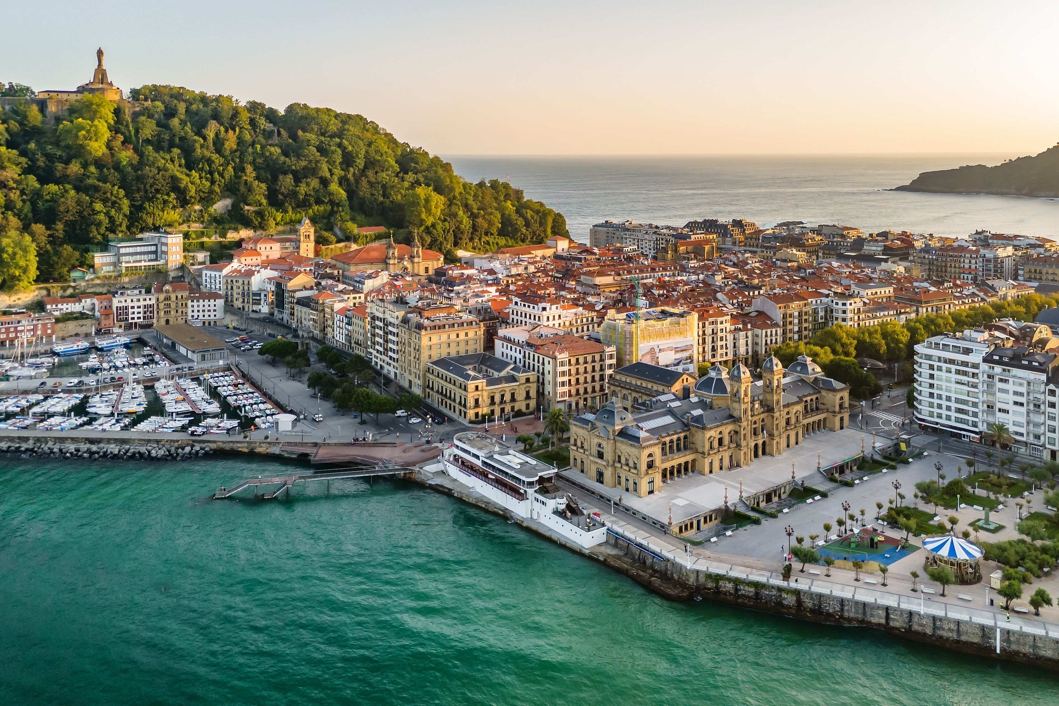 San Sebastiáns marina, stad och Monte Igueldo med en staty, badande i gyllene timmens ljus.