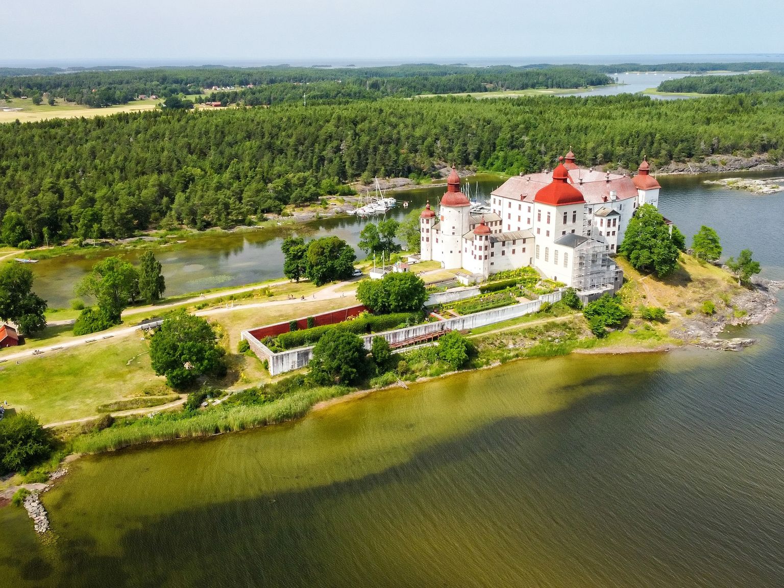 en luftig utsikt over et slott på en liten øy i midten av en innsjø omgitt av trær
