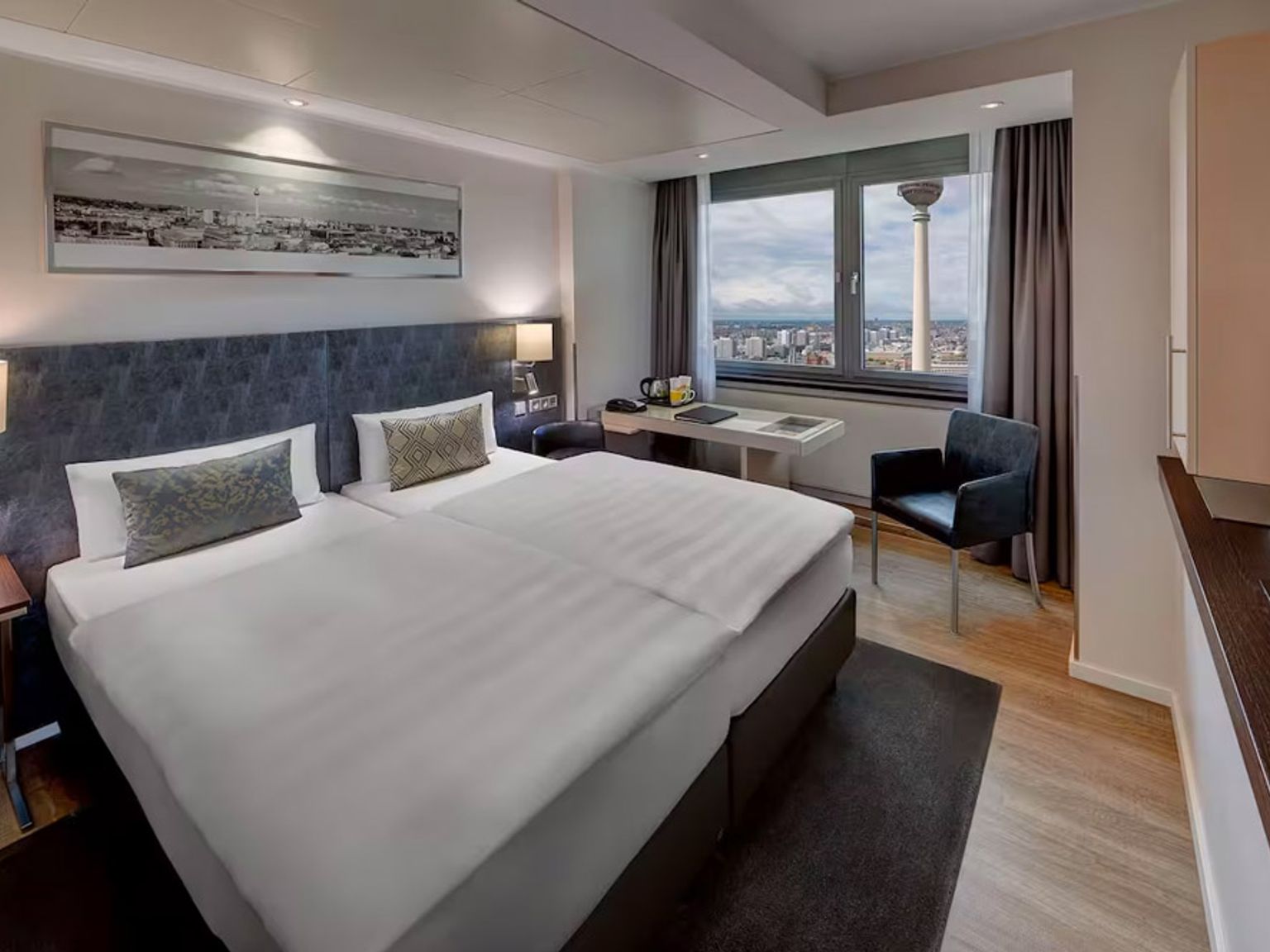 ett hotellrum med två sängar, ett skrivbord, en stol och en television