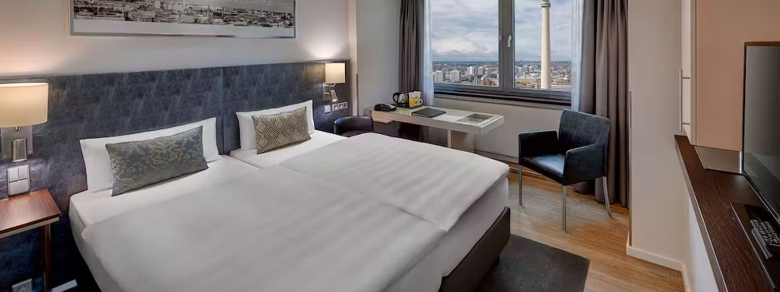 et hotellrom med to senger, et skrivebord, en stol og et fjernsyn