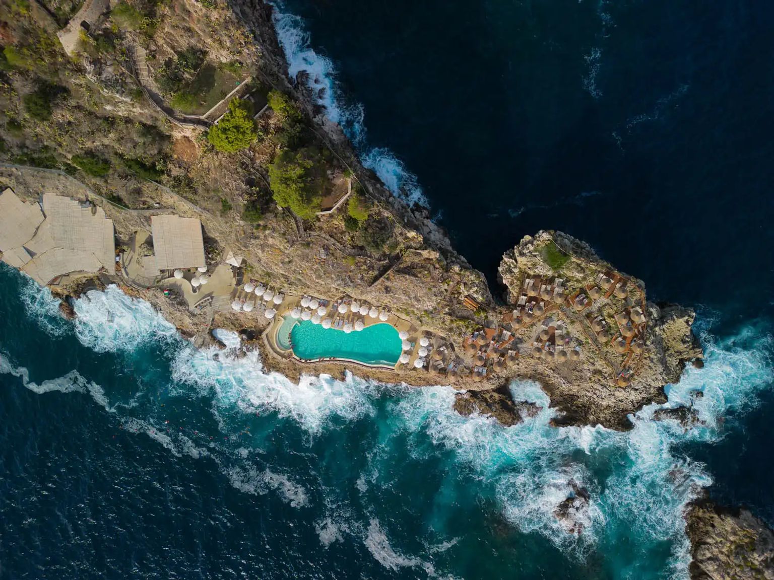en flygvy av en swimmingpool på en klippa med utsikt över havet, UNAHotels Hotel Capotaormina