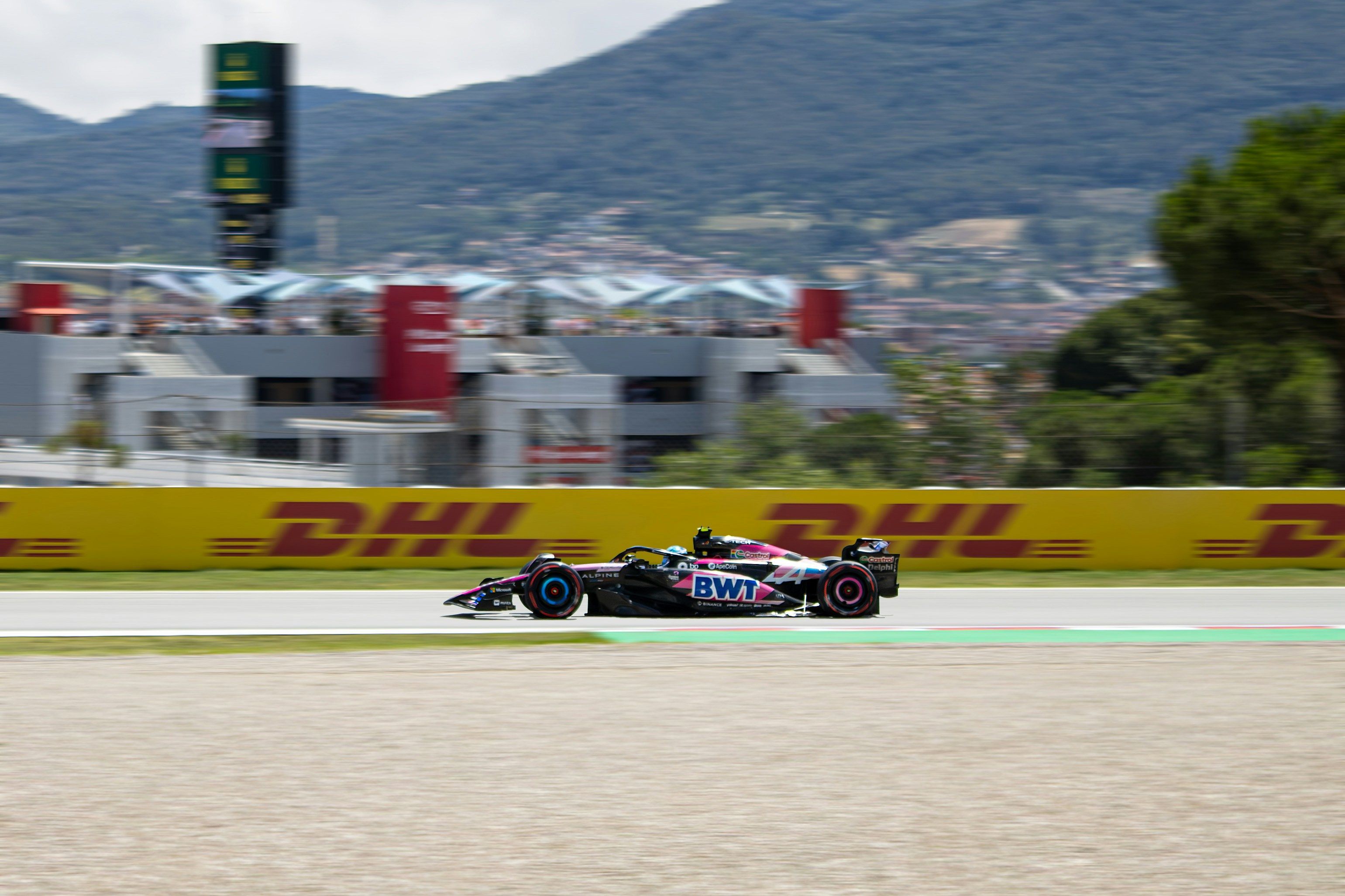 Pink and black Formula 1 car racing on a track.
