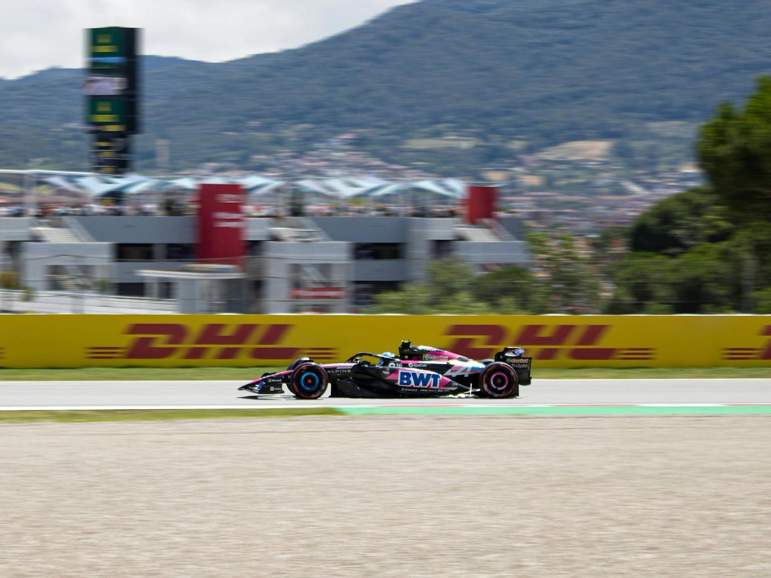 Pink and black Formula 1 car racing on a track.