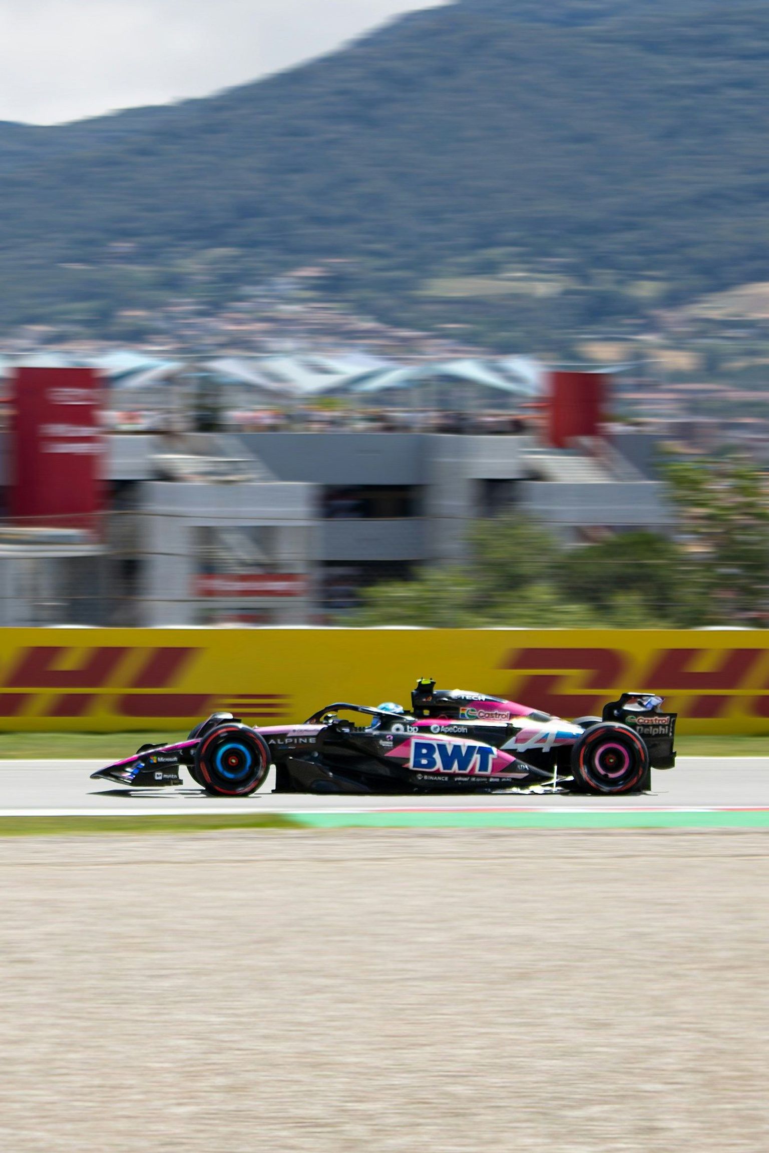 Pink and black Formula 1 car racing on a track.