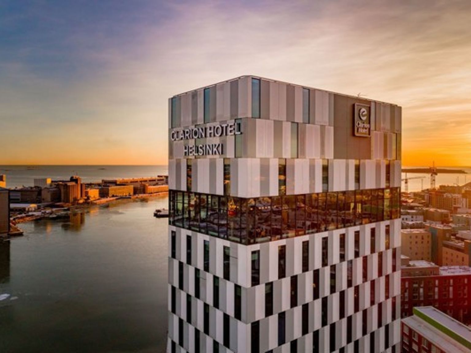 an aerial view of a tall building overlooking a body of water at sunset