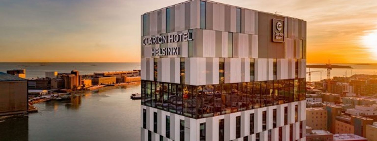 an aerial view of a tall building overlooking a body of water at sunset