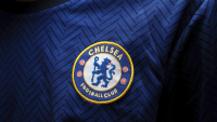 Close-up of the Chelsea Football Club logo embroidered on a blue jersey with a chevron pattern.