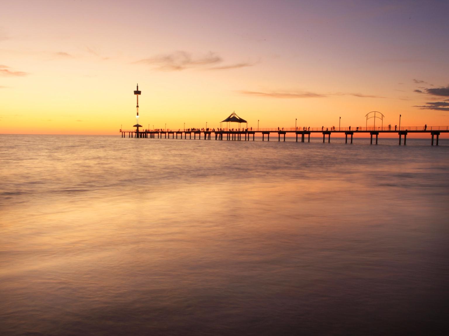 en brygge i midten av havet ved solnedgang