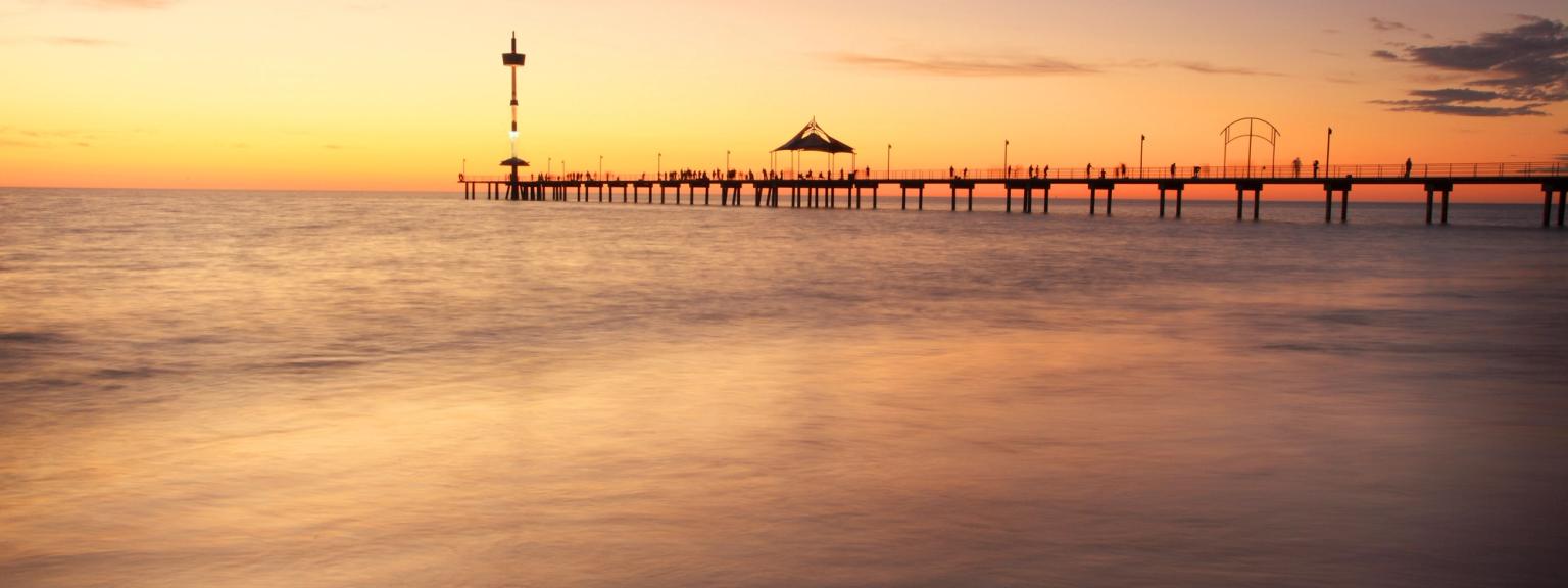 en brygge i midten av havet ved solnedgang