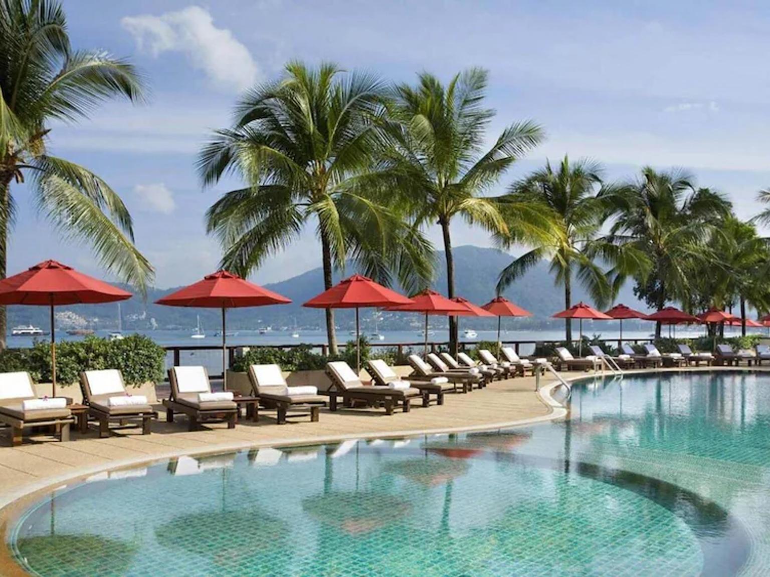 der er mange stole og parasoller omkring poolen.