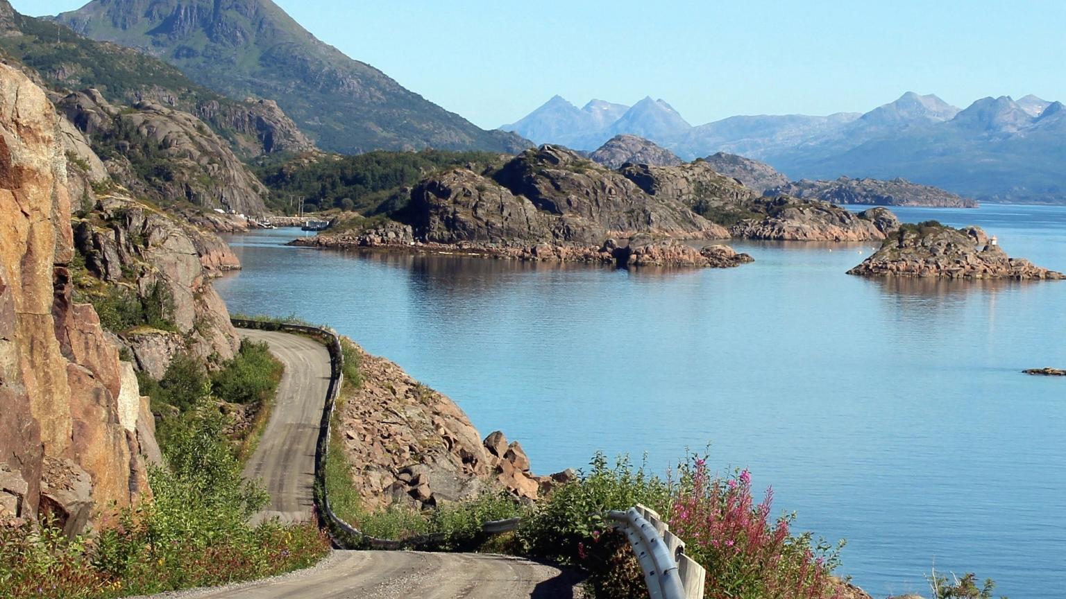 eine unbefestigte Straße, die zu einem See mit Bergen im Hintergrund führt