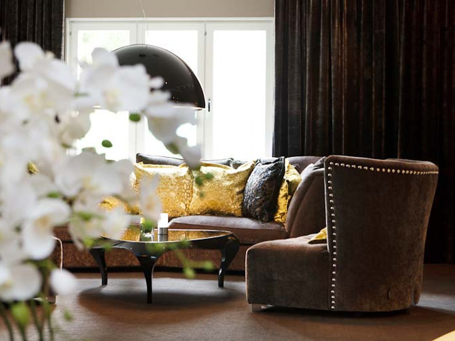 ein Wohnzimmer mit einem Sofa, Stuhl, Couchtisch und Blumen.