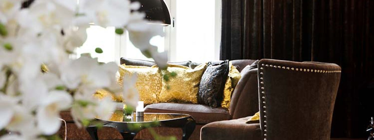 ein Wohnzimmer mit einem Sofa, Stuhl, Couchtisch und Blumen.